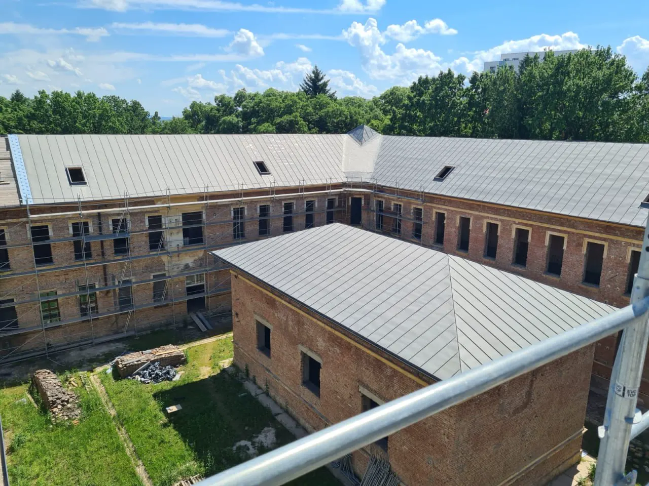Clădire istorică din cărămidă cu acoperiș nou din tablă fălțuită, văzută de pe schelă