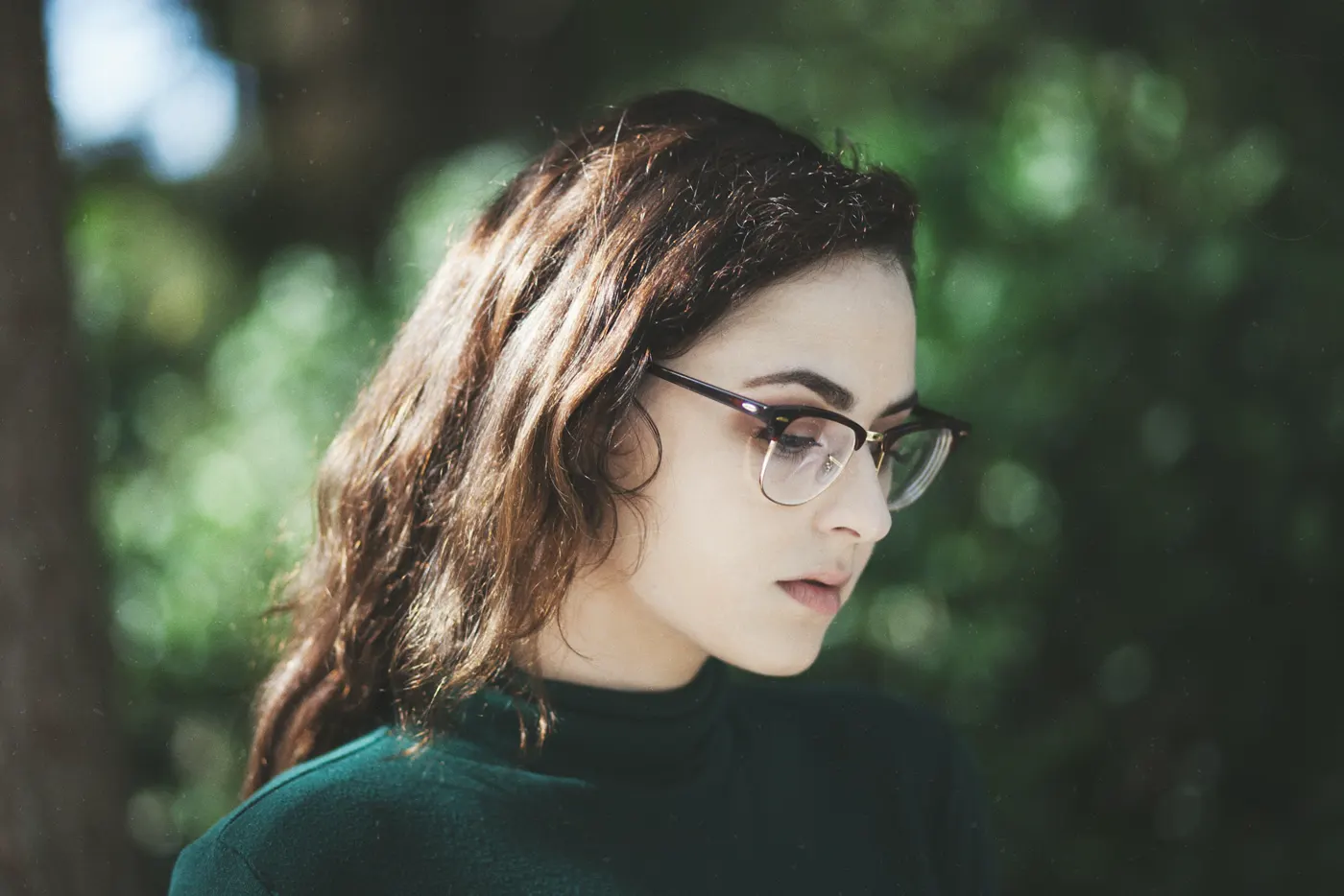Femeie cu ochelari cu ramă din acetat și metal auriu, în lumină naturală