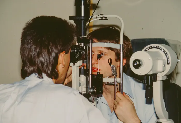 Optometrist care examinează ochiul unei paciente la biomicroscop